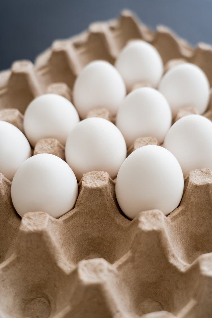 Huevos de pollo naturales en bandeja de cartón sobre fondo gris borroso - Foto, Imagen