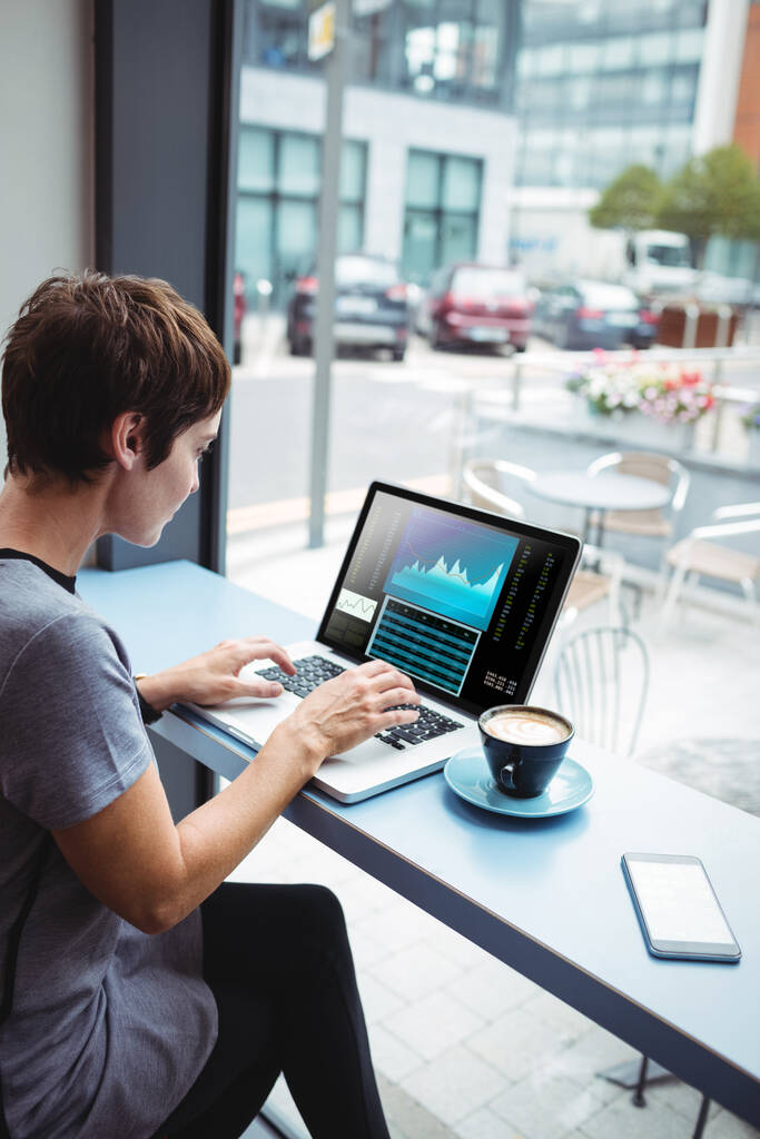 Zakenvrouw die een kopje koffie od terwijl het gebruik van laptop op kantoor - Foto, afbeelding