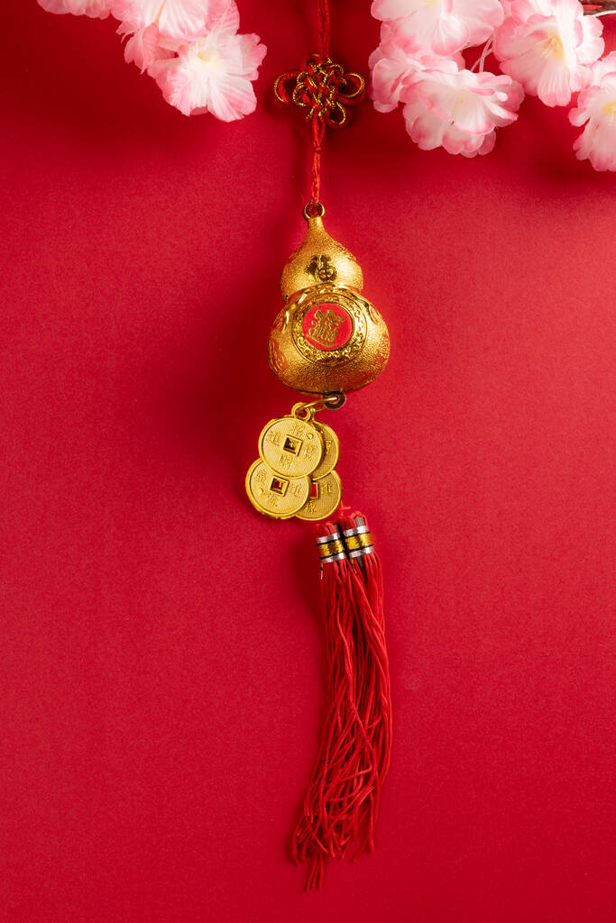 Σύνθεση από κοντά άνθη κερασιάς και κινέζικη διακόσμηση σε κόκκινο φόντο. Κινέζικο νέο έτος, παράδοση και εορταστική έννοια. - Φωτογραφία, εικόνα