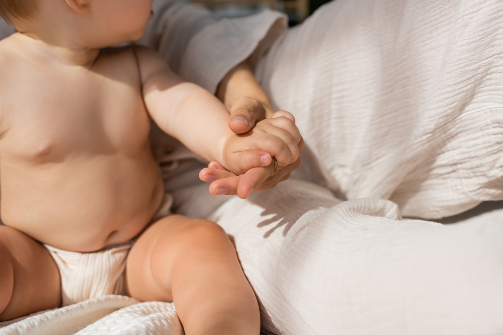 καλλιεργημένη άποψη της μητέρας κρατώντας τα χέρια με το κοριτσάκι στο υπνοδωμάτιο  - Φωτογραφία, εικόνα