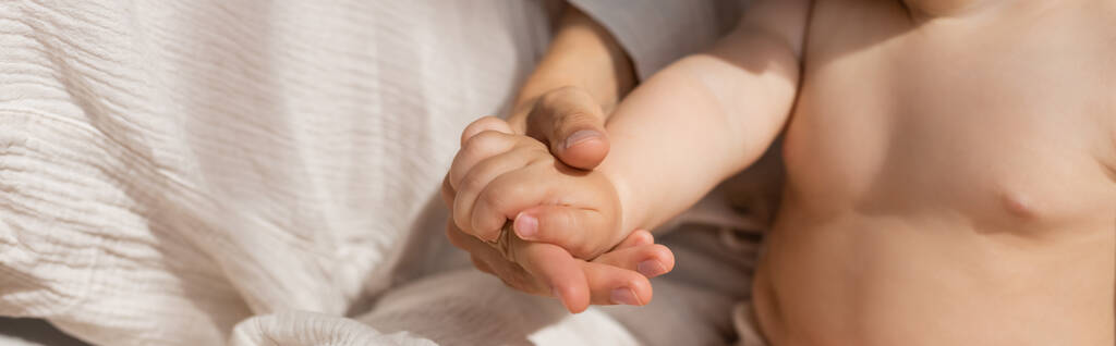 cropped view of mother holding hands with infant girl in bedroom, banner - Photo, Image