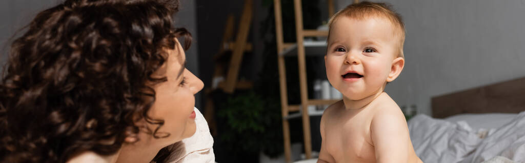 Äiti kihara tukka katselee onnellinen vauva tytär makuuhuoneessa, banneri - Valokuva, kuva