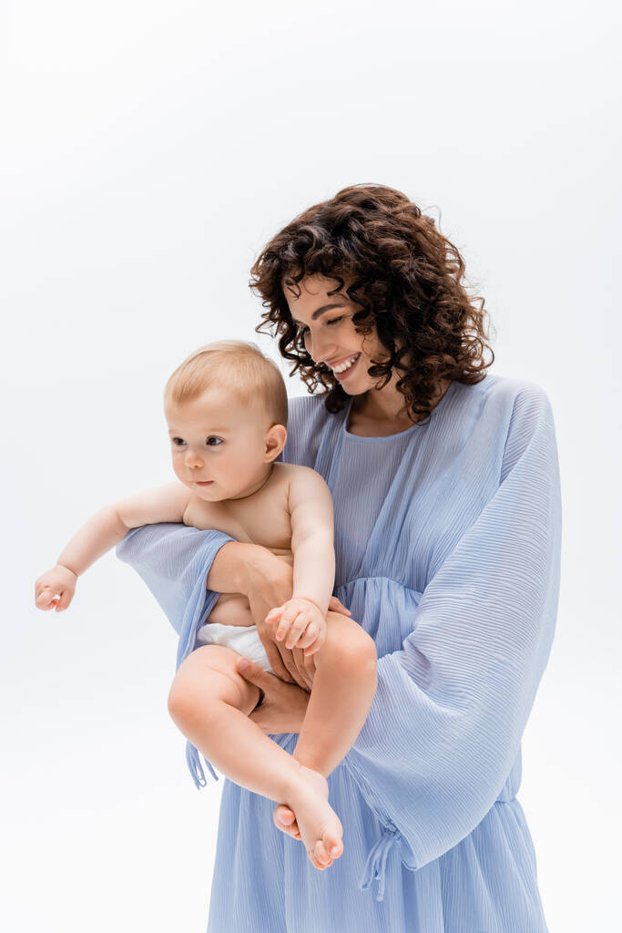 Boldog szülő kék ruhában nézi csecsemő lánya elszigetelt fehér  - Fotó, kép