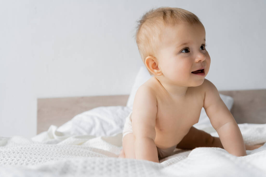 Csecsemő gyermek bugyiban ül a fehér ágynemű otthon  - Fotó, kép
