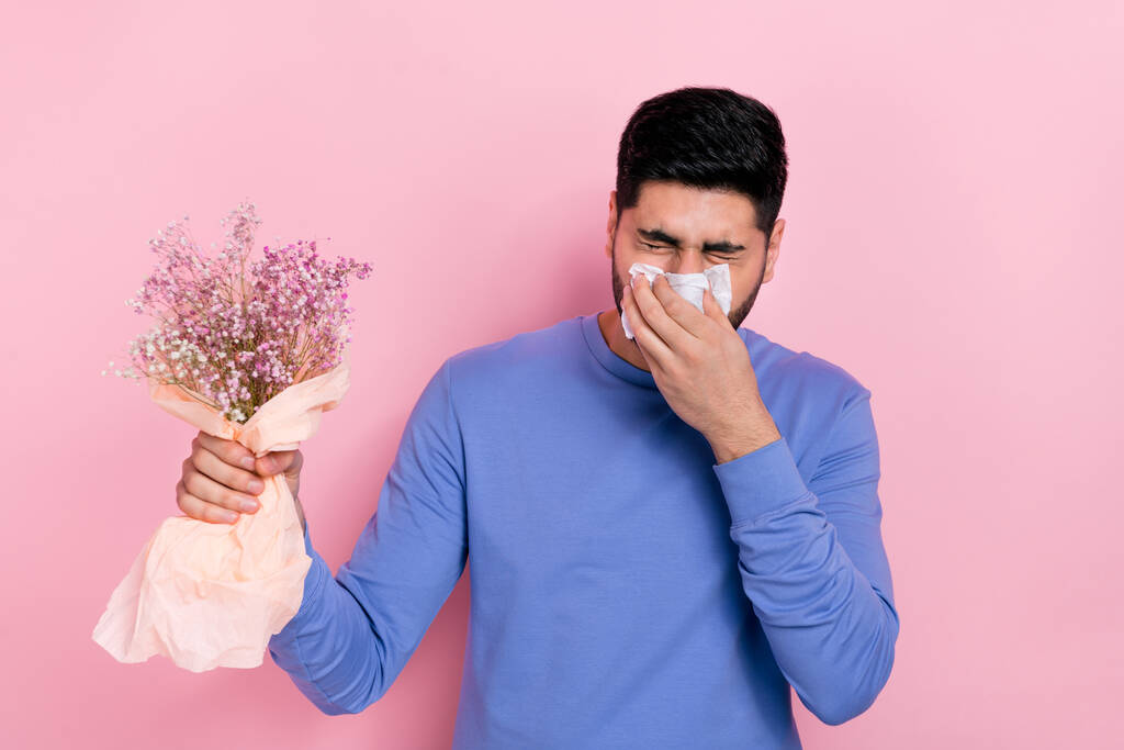 Foto von unglücklichen traurigen arabischen Kerl gekleidet blauen Pullover weht Nase Blumen Allergie isoliert rosa Farbe Hintergrund. - Foto, Bild