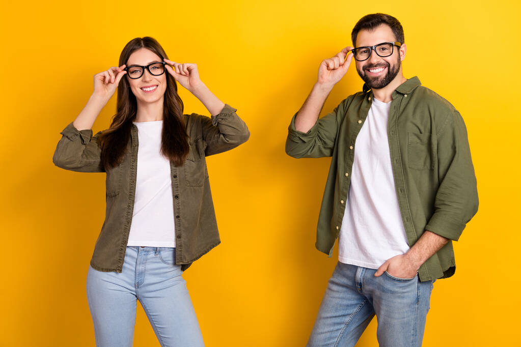 Muotokuva houkutteleva iloinen fiksu fiksu pari koskettaa silmälasit poseeraa yli kirkkaan keltainen väri tausta. - Valokuva, kuva