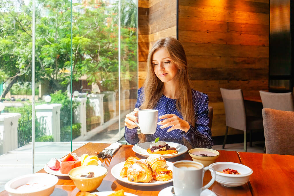 Attractive woman on breakfast in hotel restaurant. Businesswoman on meeting dine in modern cafe, drinking coffee. Business lunch concept - Photo, image
