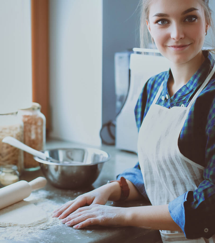 Όμορφη γυναίκα μαγείρεμα κέικ στην κουζίνα στέκεται κοντά στο γραφείο - Φωτογραφία, εικόνα