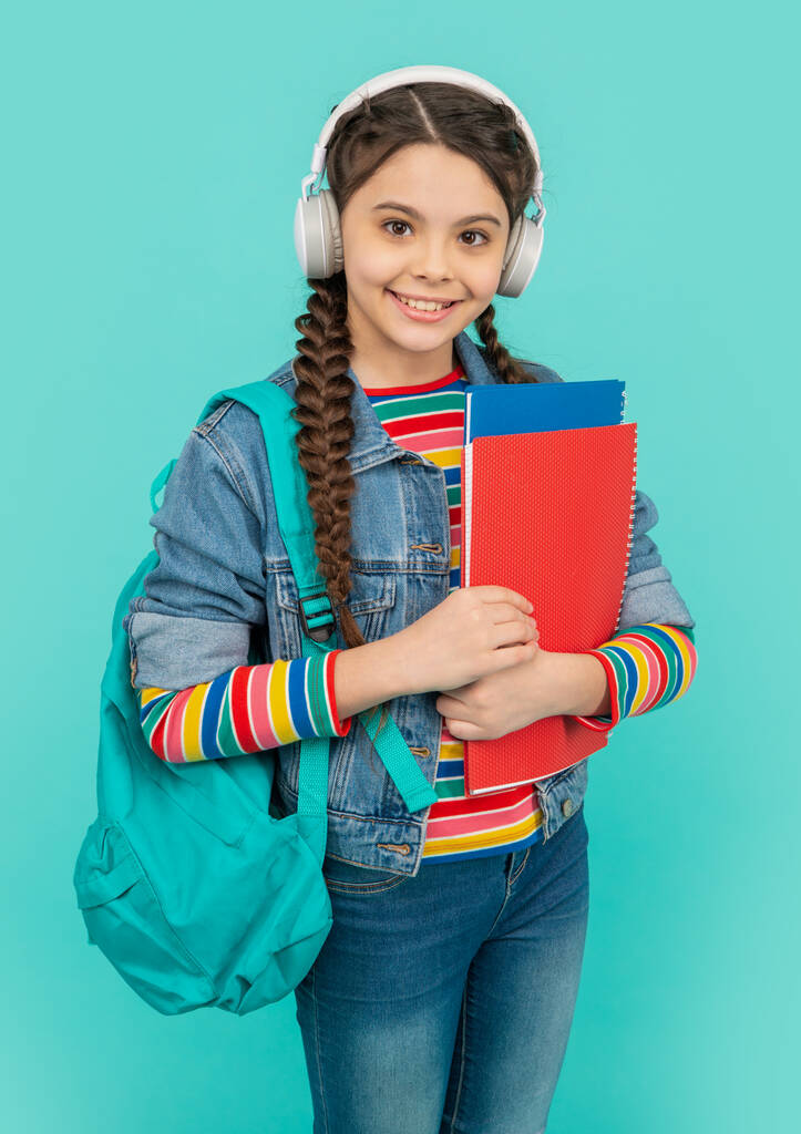 Boldog tinédzser, aki audiobookat hallgat fejhallgatóban. Boldog tinédzser lány hallgat audio leckét kék háttér. Hallgatási képességek. Iskolai oktatás. - Fotó, kép