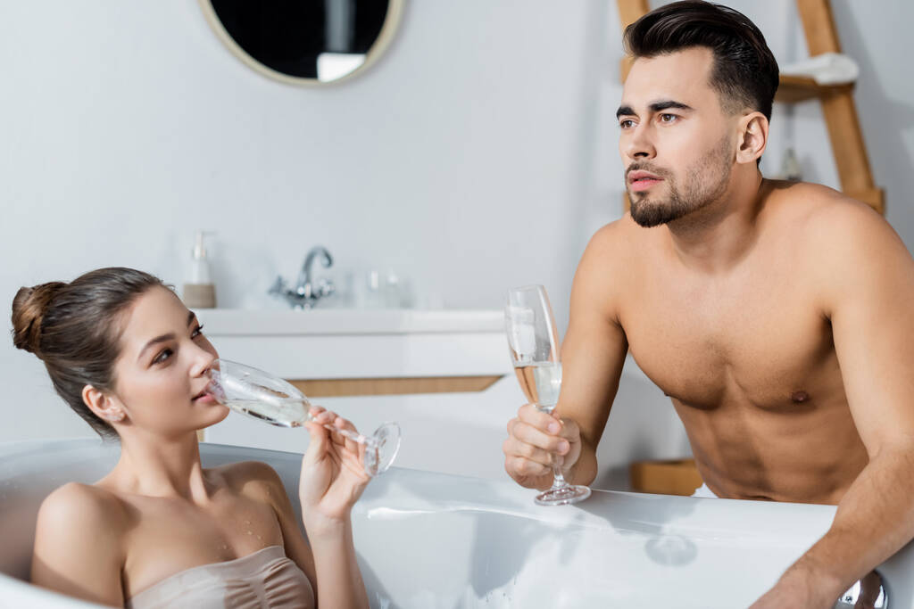 femme sexy buvant du champagne dans la baignoire et regardant petit ami coûteux - Photo, image