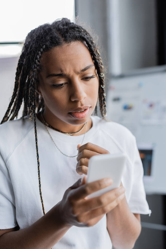 Empresaria afroamericana preocupada usando teléfono celular en la oficina  - Foto, imagen