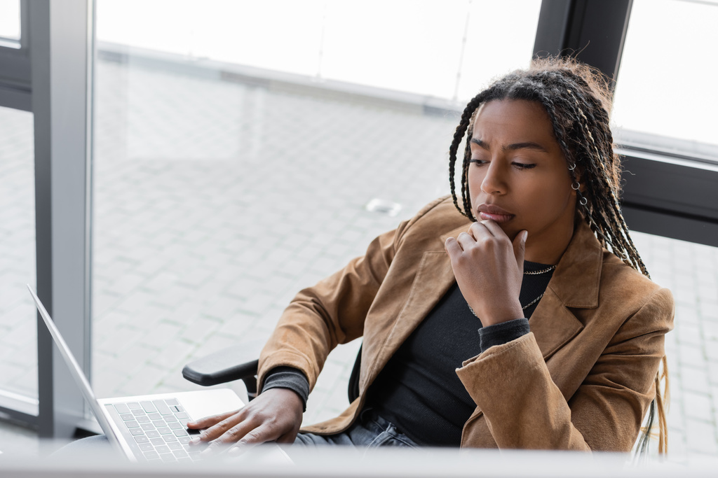Εστιασμένη Αφροαμερικανίδα επιχειρηματίας που χρησιμοποιεί φορητό υπολογιστή στο γραφείο  - Φωτογραφία, εικόνα