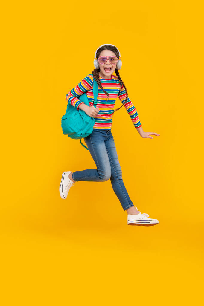 Mutlu enerjik genç kız okuldan sonra atlıyor sarı arka plan, okul. Okula geri dön.. - Fotoğraf, Görsel