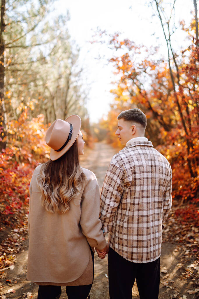 Una giovane coppia innamorata passeggia nel parco in una giornata autunnale. Godere del tempo insieme. - Foto, immagini