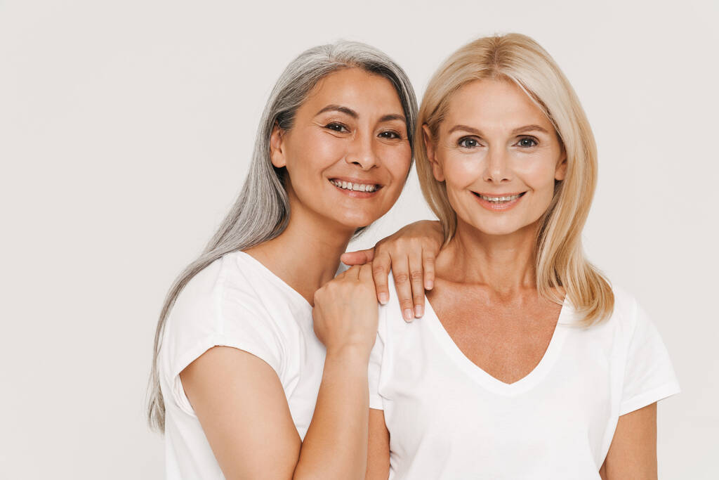 Mature multiracial women with gray hair wearing t-shirts smiling at camera isolated over white background - Photo, Image