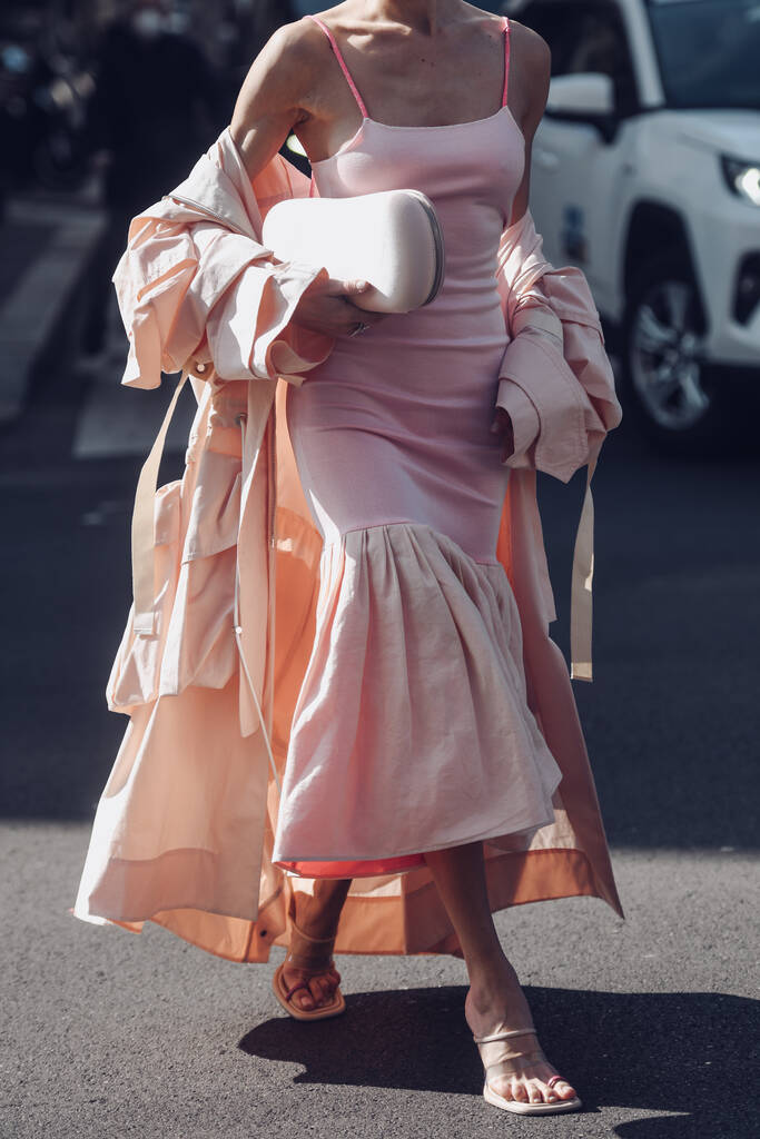 Уличный стиль, женщина в бледно-розовом цистерне на верхней части трубки колени с вышитым бледно-розовым платьем midi, бледно-розовый огромный длинный плащ окопа и розовые сандалии. - Фото, изображение