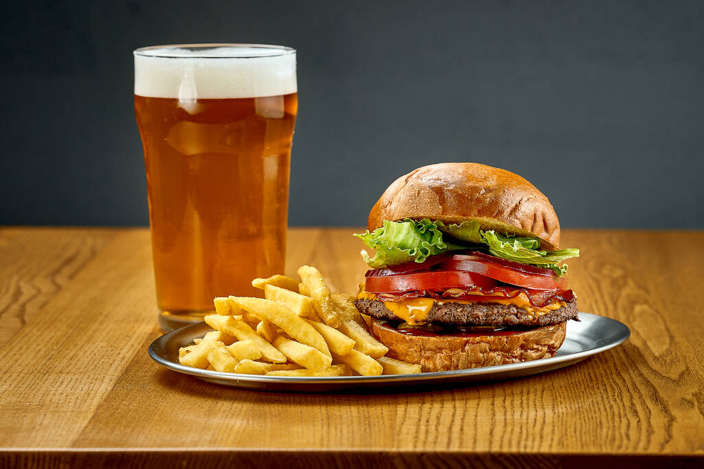 Velký šťavnatý burger se zeleninou a sklenicí piva. Detailní záběr, selektivní zaměření - Fotografie, Obrázek