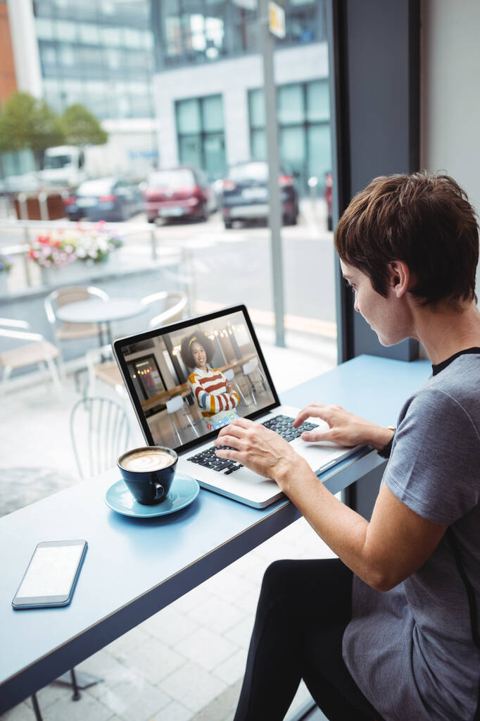 İş kadını ofiste dizüstü bilgisayar kullanırken kahve içiyor. - Fotoğraf, Görsel