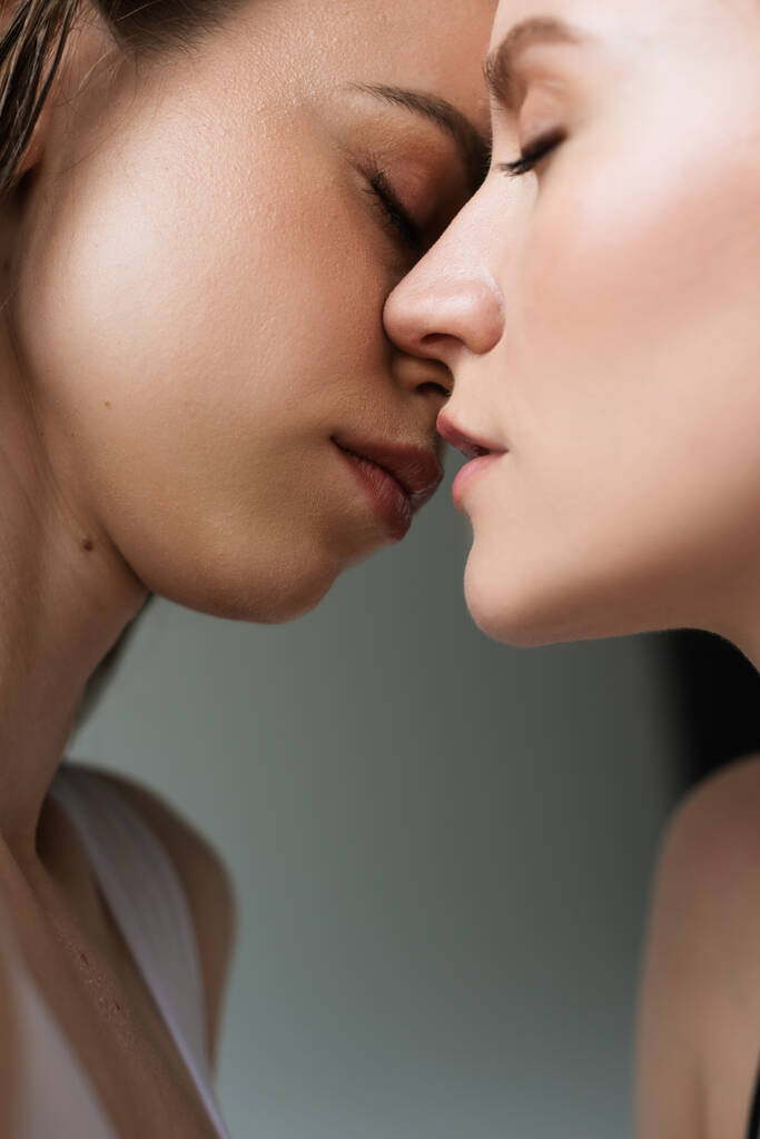 Gri renkte yalnız genç lezbiyen kadınların öpüşmesine yakından bakın. - Fotoğraf, Görsel