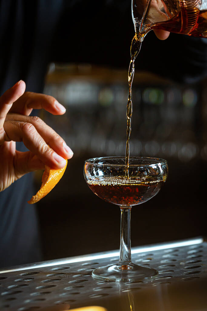 O barman prepara um coquetel em um restaurante usando raspas de laranja. Foto de alta qualidade - Foto, Imagem
