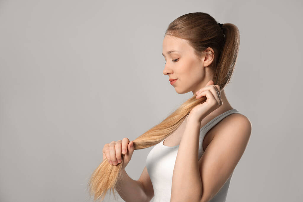Teenage κορίτσι με ισχυρή υγιή μαλλιά σε ανοιχτό γκρι φόντο, χώρος για κείμενο - Φωτογραφία, εικόνα