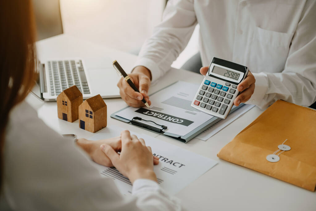 Agente corretor imobiliário escrevendo contrato e mostrando calculadora com preço  - Foto, Imagem