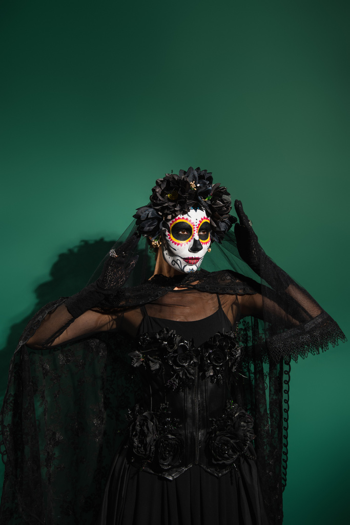 Žena v strašidelný Santa Muerte kostým a make-up stojící na zeleném pozadí  - Fotografie, Obrázek