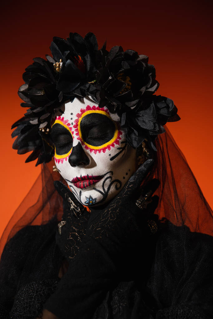 Portrait de femme en costume d'Halloween et maquillage du crâne de sucre posant sur fond rouge  - Photo, image