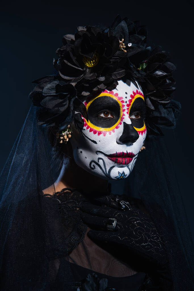 portrait of woman in black wreath and mexican catrina makeup on dark blue background - Photo, Image