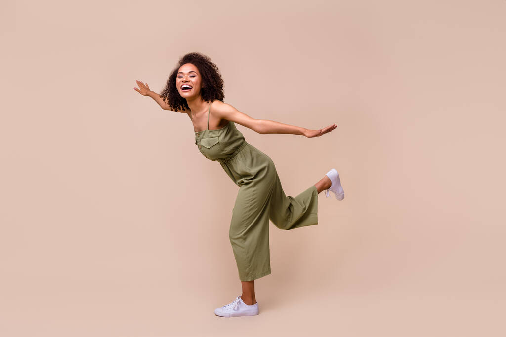 Ganzkörper-Foto von funky brünette Frau spielen tragen Gesamtschuhe isoliert auf beige Farbhintergrund. - Foto, Bild