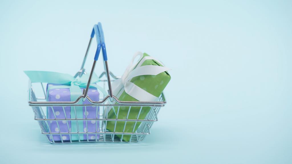 cesta de la compra con cajas de regalo envueltas en fondo azul - Foto, Imagen