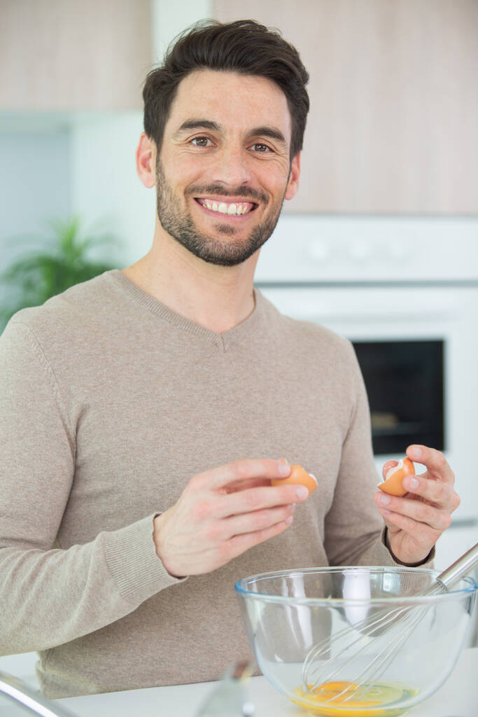 Ein Mann verquirlt Eier in einem tiefen Teller - Foto, Bild