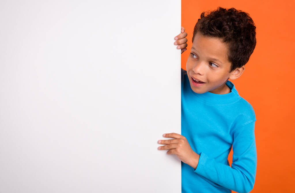 Foto ritratto di affascinante piccolo ragazzo allievo impressionato sguardo vuoto spazio vestito elegante vestito blu isolato su sfondo di colore arancione. - Foto, immagini