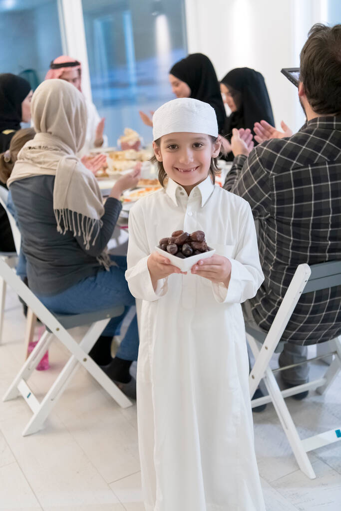 Eid Mubarak muslimská rodina s Iftar večeře malý chlapec drží talíř plný sladkých doprovod rozbít hostinu. Jíst tradiční jídlo během ramadánského svátku měsíce doma. The Islamic Halal Eating - Fotografie, Obrázek