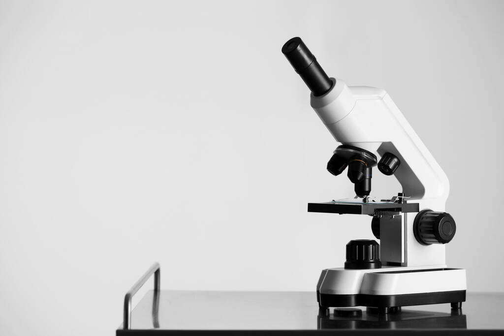 Microscópio moderno em mesa de metal contra fundo claro. Espaço para texto - Foto, Imagem