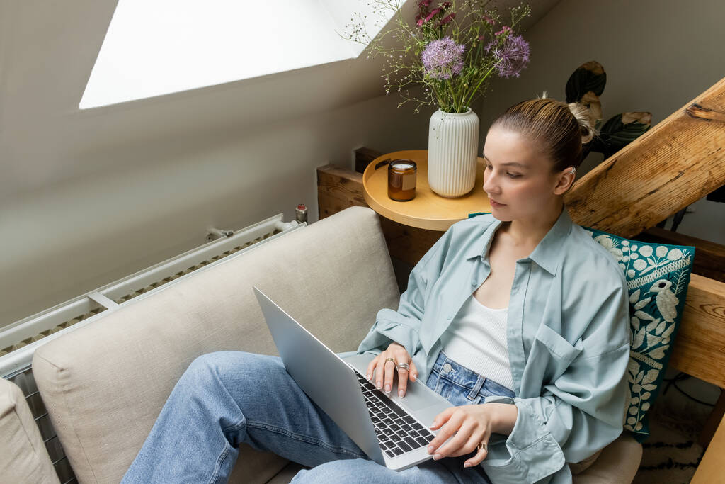 Fiatal nő használja laptop, miközben ül a kanapén otthon  - Fotó, kép