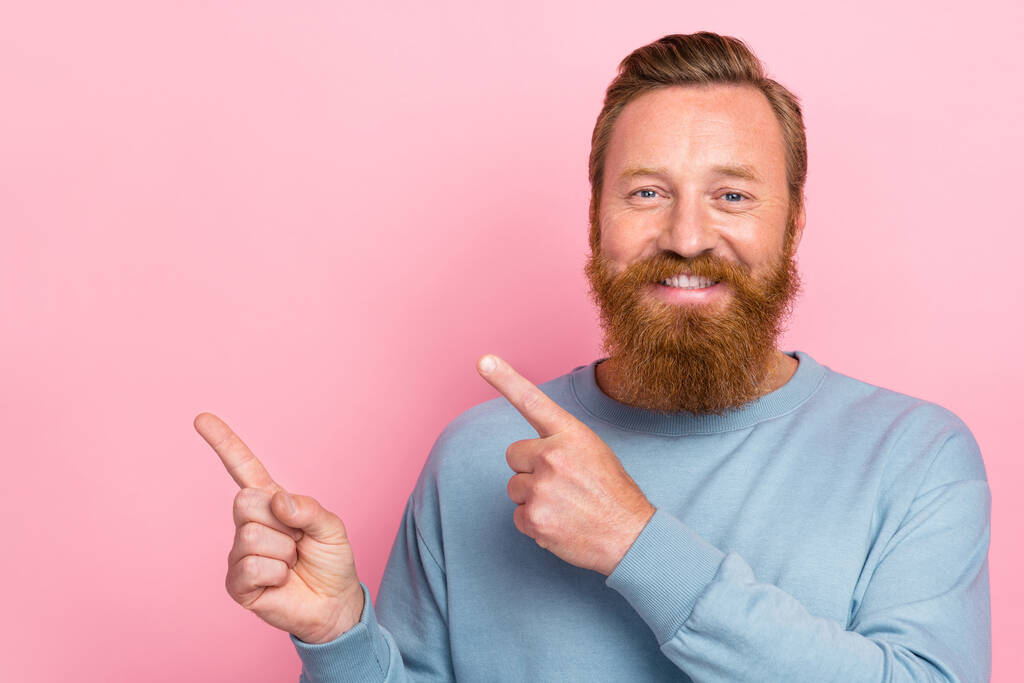 Portrait photo of young attractive bearded redhair man smile toothy fingers pointing empty space advert isolated on pink color background. - Photo, Image