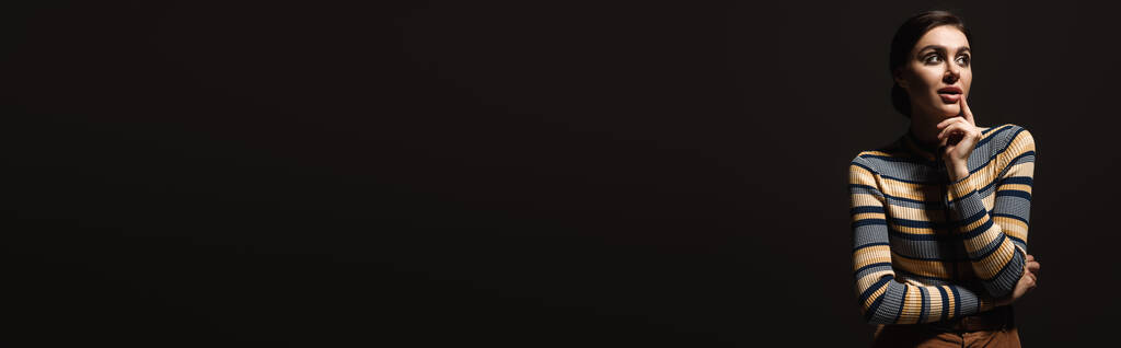 unenomainen nuori nainen raidallinen poolokaula etsii pois eristetty musta, banneri - Valokuva, kuva