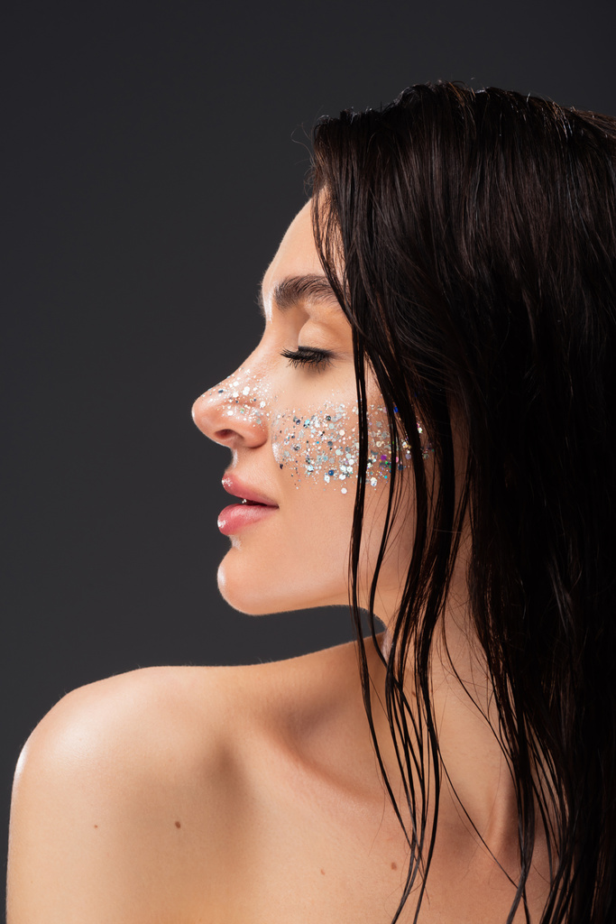 profile of young brunette woman with natural makeup and sparkling glitter on cheeks isolated on grey - Photo, Image