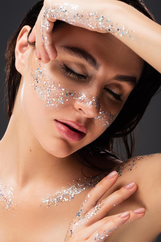 portrait of young woman with glitter on cheeks and closed eyes isolated on grey  - Photo, Image