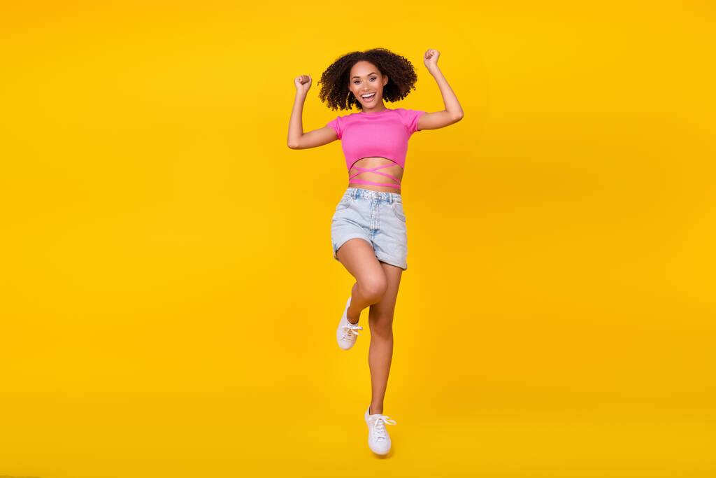 Täyspitkä kuva funky brunette nuori nainen hypätä kulumista top shortsit saappaat eristetty oranssi väri tausta. - Valokuva, kuva