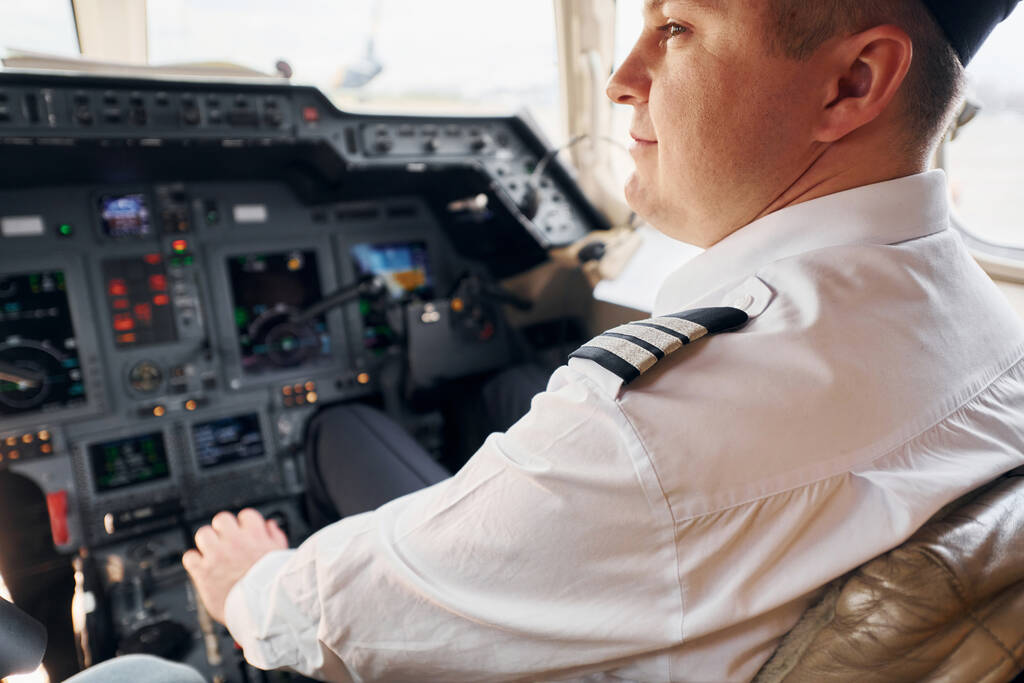 Sakin atmosfer. Resmi kıyafetli pilot kokpitte oturur ve uçağı kontrol eder.. - Fotoğraf, Görsel