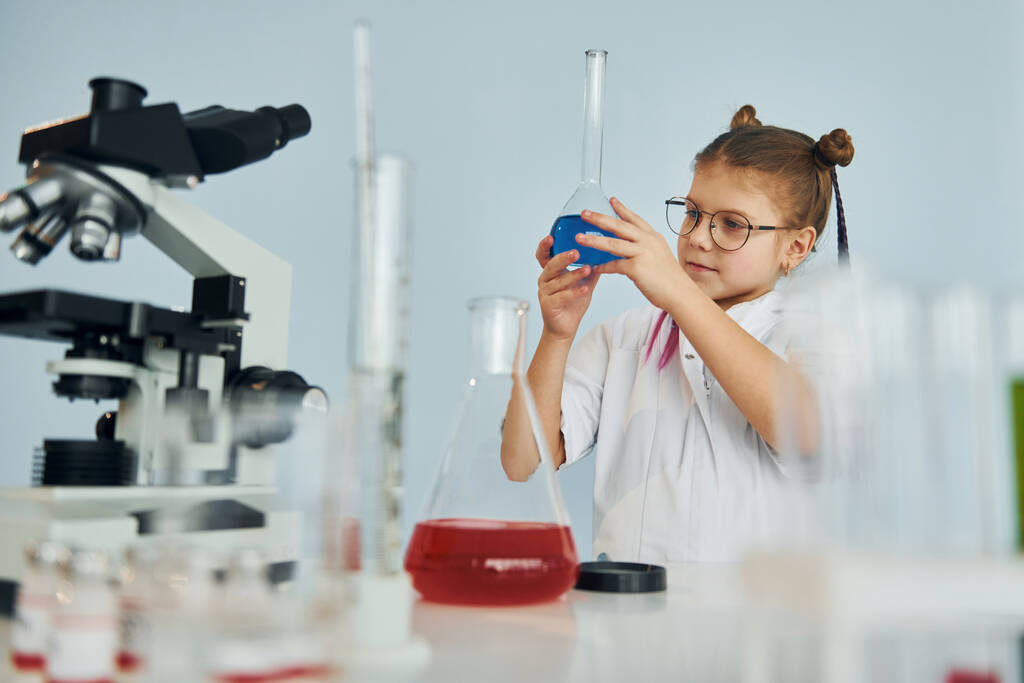 Little girl in coat playing a scientist in lab by using equipment. - Photo, Image