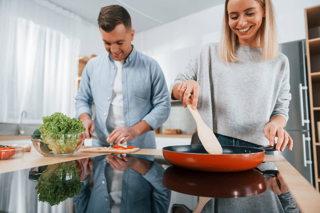 Faire frire la nourriture dans une poêle. Couple préparer la nourriture à la maison sur la cuisine moderne. - Photo, image