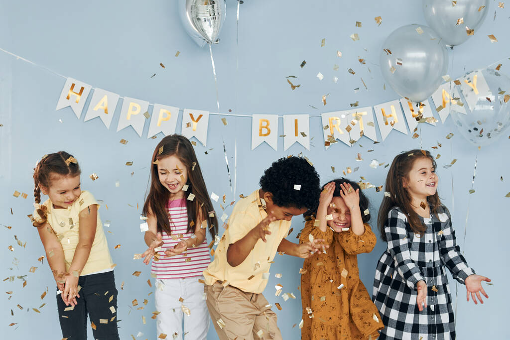 Повітряні кульки і конфетті. Діти на святкуванні дня народження в приміщенні розважаються разом
. - Фото, зображення
