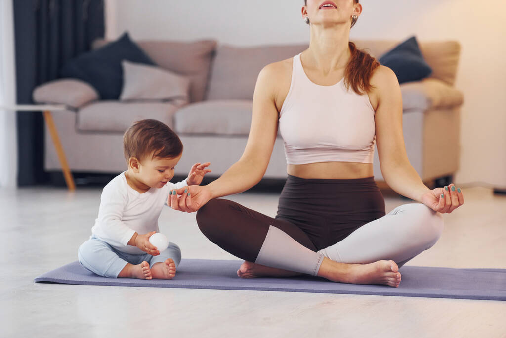 Concentrato sugli esercizi di yoga. Madre con la sua figlioletta è a casa insieme. - Foto, immagini