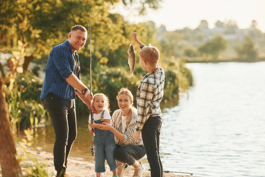 Maaseudulla. Isä ja äiti poikansa ja tyttärensä kanssa kalastamassa ulkona kesällä. - Valokuva, kuva
