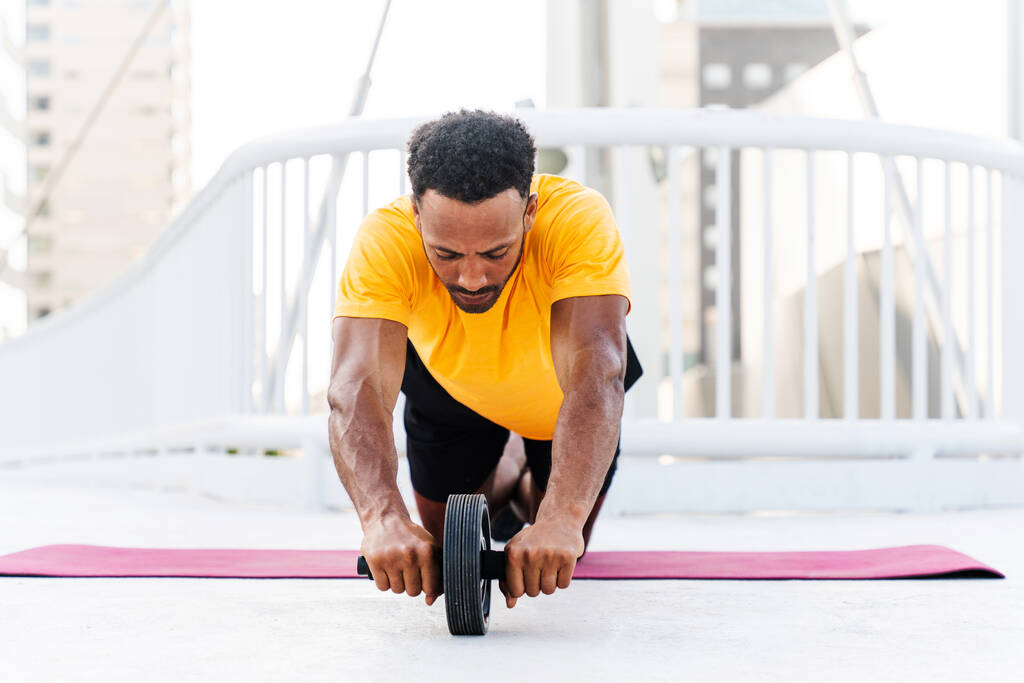 Zwarte Spaanse sportman training buiten in de stad - Afrikaanse man met fit gespierd lichaam doet functionele training om cardio, lichaamsspieren en buikspieren core trainen - Foto, afbeelding