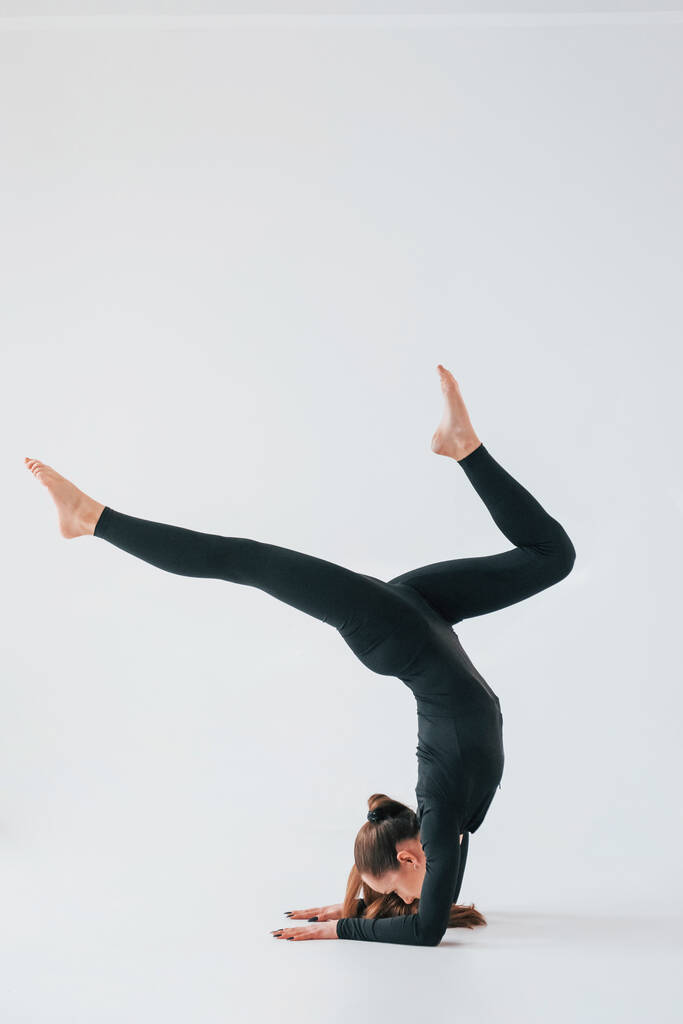 Практикуйтесь. Молодая женщина в спортивной одежде занимается гимнастикой в помещении. - Фото, изображение