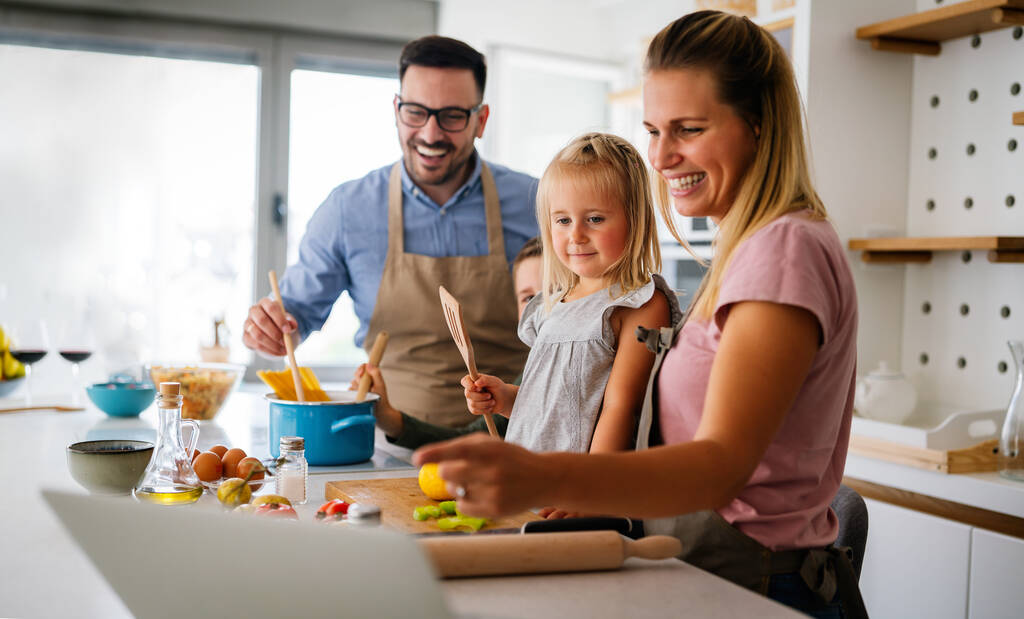 Gelukkig jong gezin bereidt gezond voedsel samen in de keuken. Mensen geluk koken concept - Foto, afbeelding